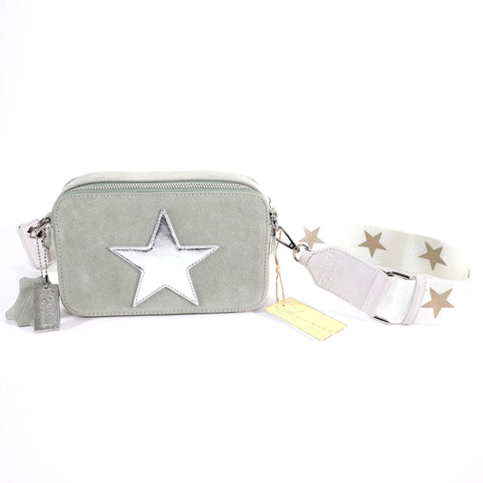 A silver suede shoulder bag with a star shape on the front, two detachable shoulder straps, and a large silver slip pocket on the back.